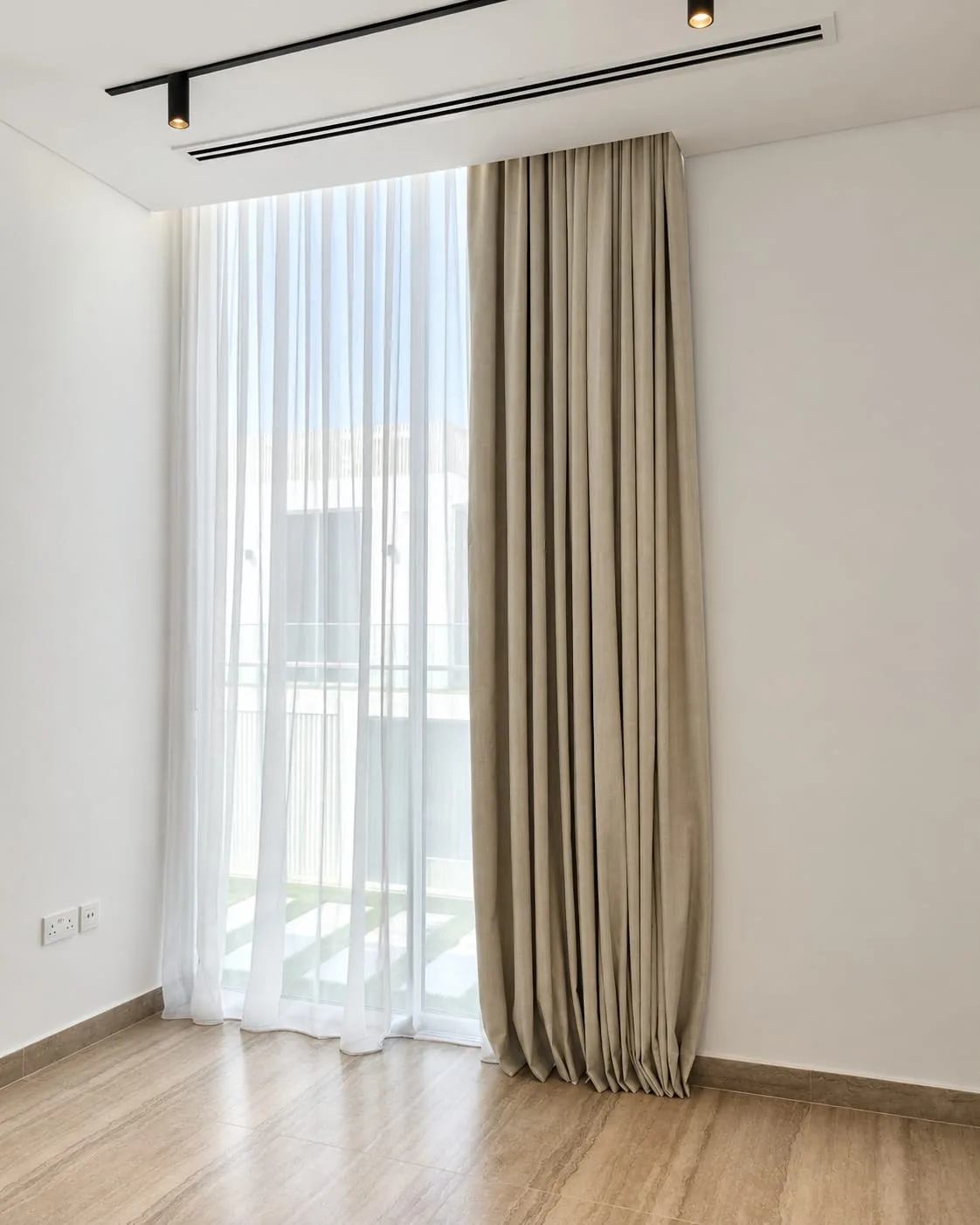 Taupe curtain and white sheer hung from a ceiling track beside a balcony door
