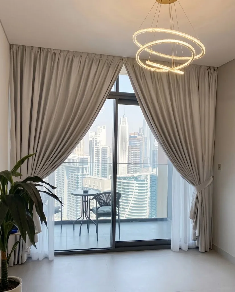 Grey pleated curtains framing a balcony with a Dubai Marina skyline view