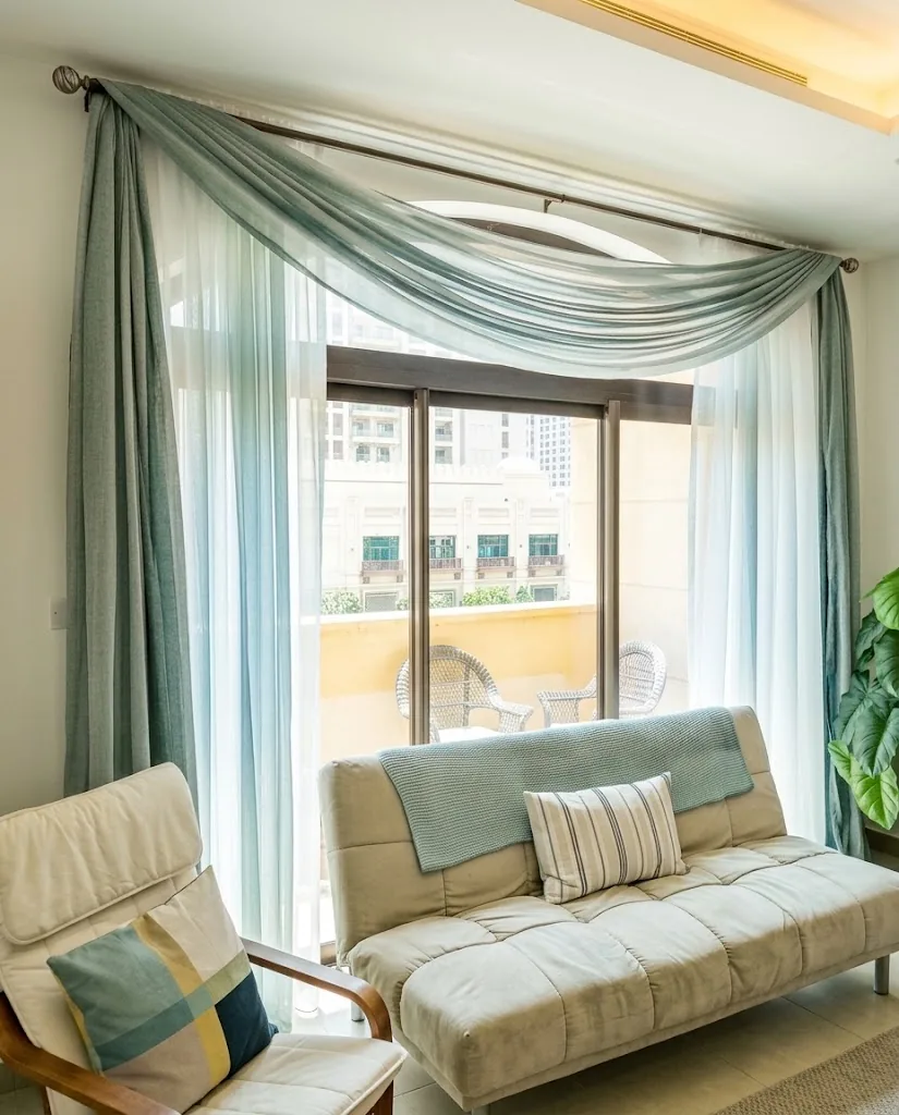 Sage scarf swag over white sheer curtains in a living room