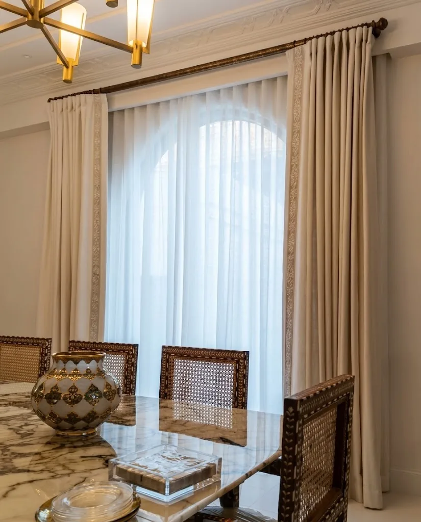 Beige curtains and white sheers on an arched dining room window