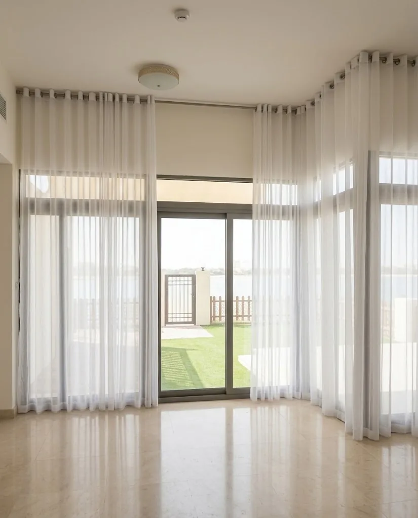 White eyelet sheers around corner windows in a living room