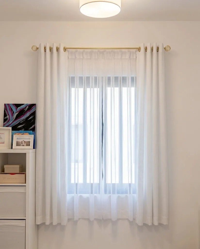 White eyelet sheer curtains on a gold rod