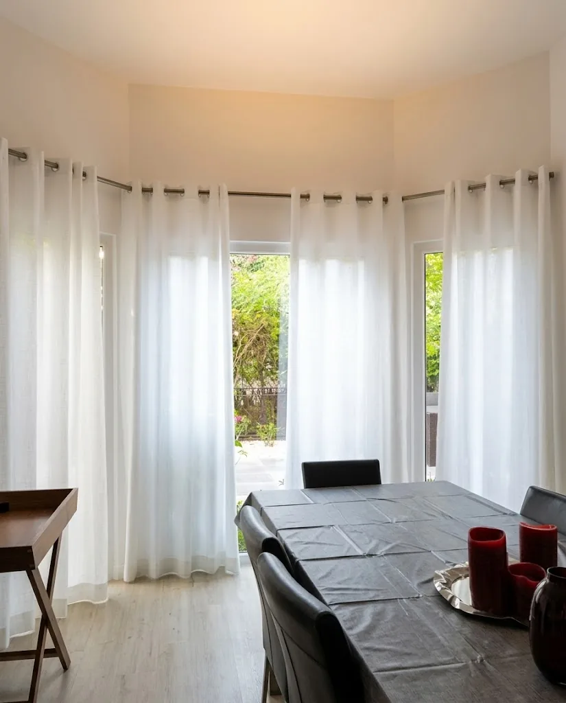 Eyelet sheer curtains around a dining room bay window