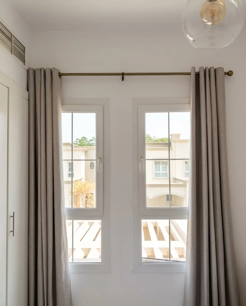 Grey eyelet curtains on French windows in a bedroom