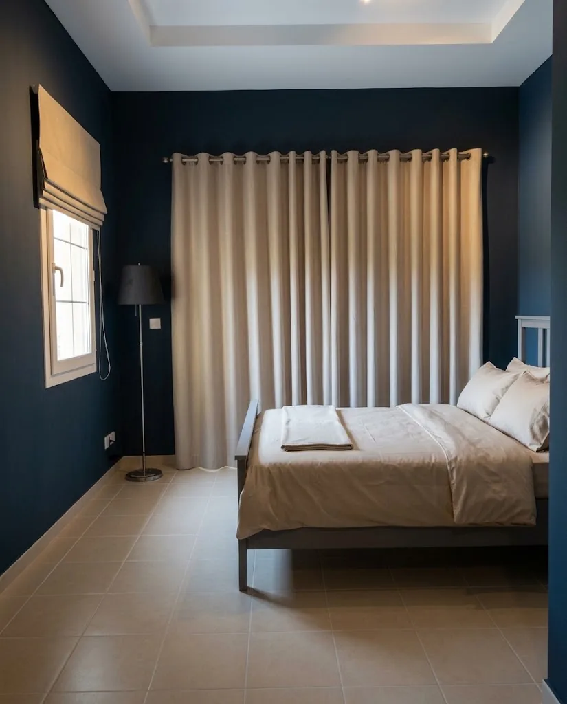 Beige eyelet curtains in a bedroom with a navy feature wall
