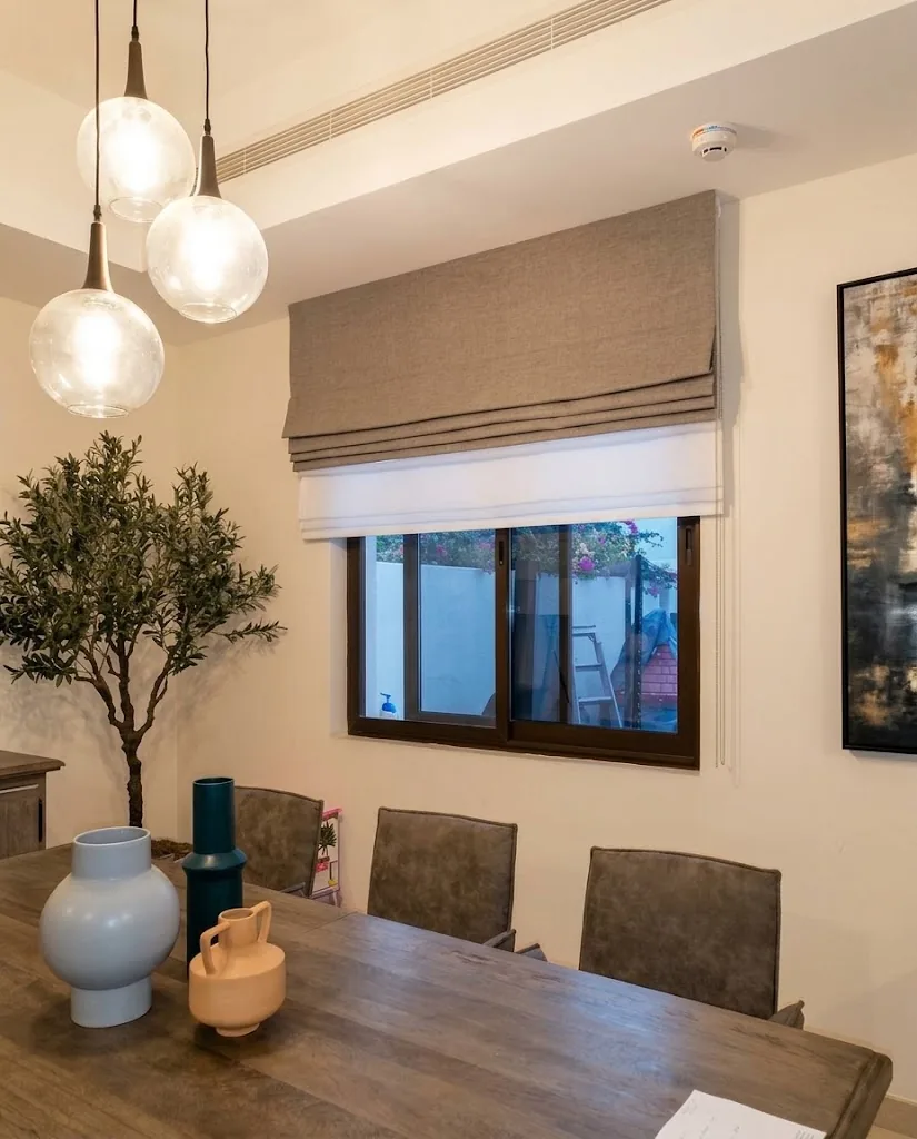Taupe Roman blind above a dining table with pendant lights