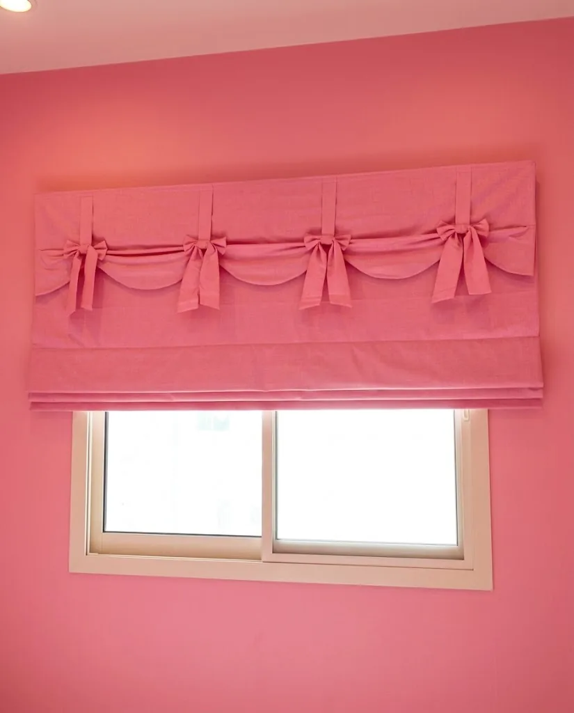 Pink tie-up Roman blind with bows in a children's room