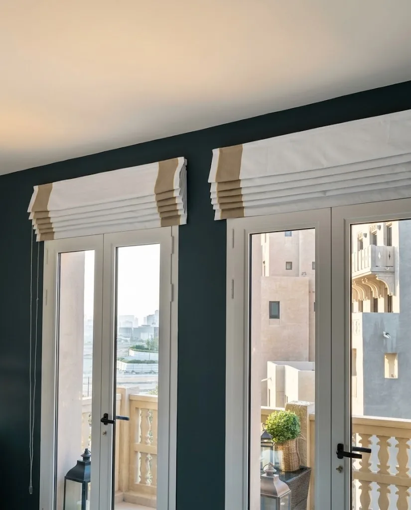 Striped Roman blinds above French doors against a teal wall