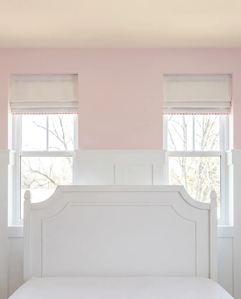 Cream Roman blinds in a girl's bedroom with a pink wall