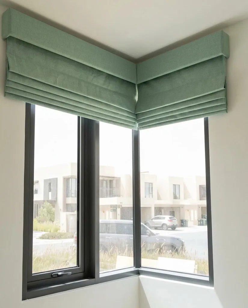 Sage green Roman blinds on a corner window