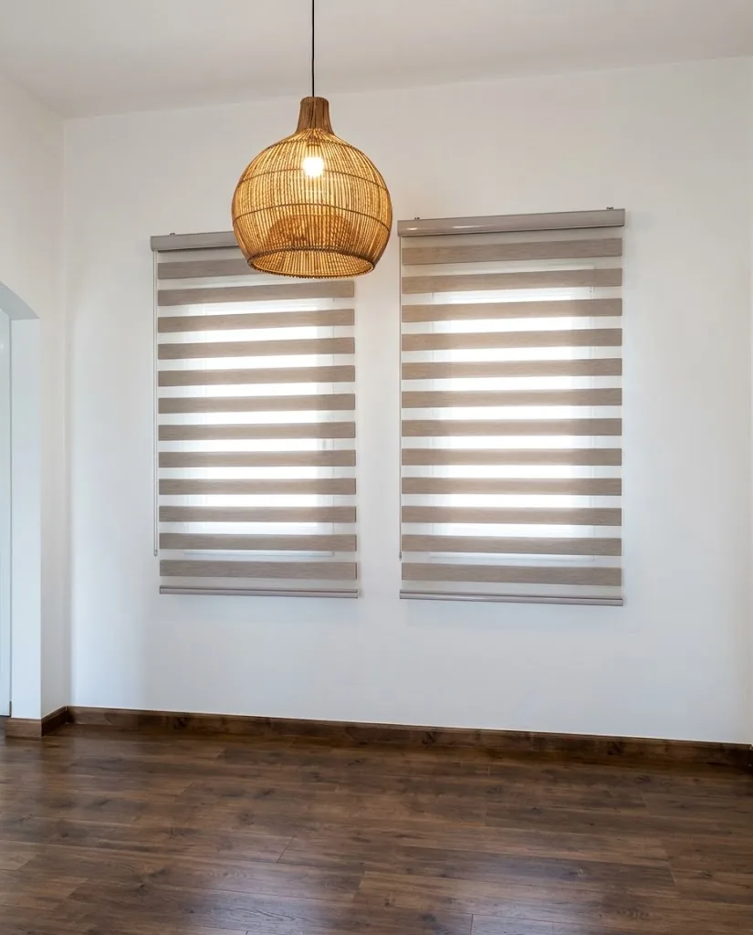 Grey zebra blinds on two windows under a rattan pendant