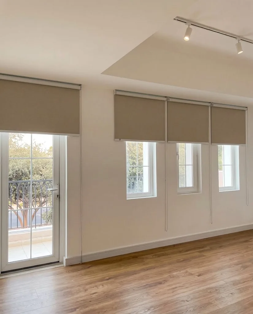Taupe roller blinds on a row of living room windows