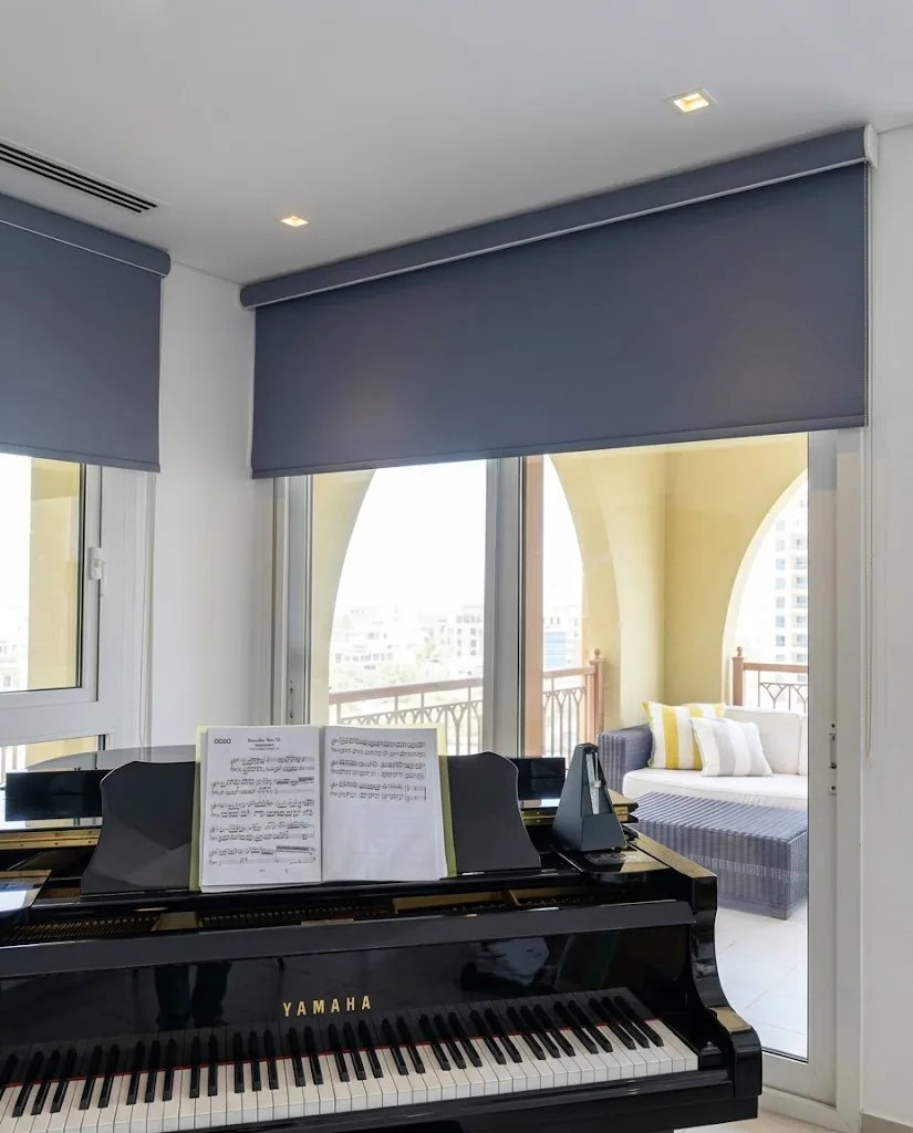 Blue-grey roller blind above a glass door in a piano room
