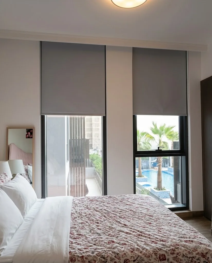 Grey roller blinds in a bedroom overlooking a pool