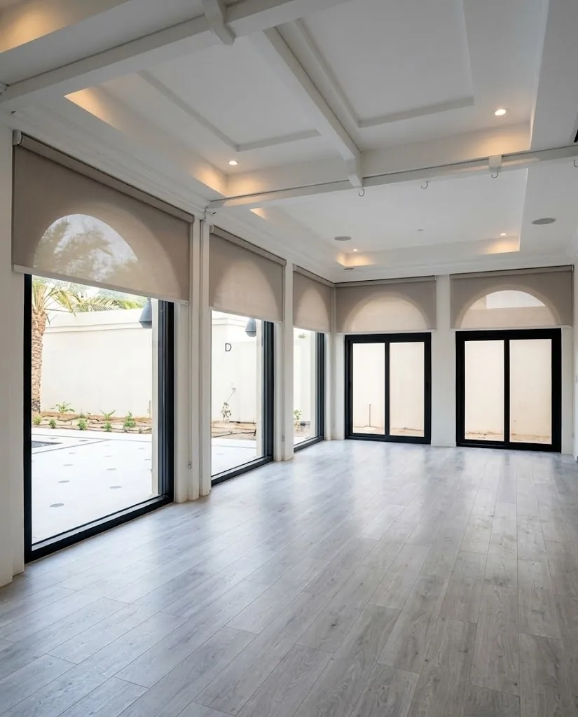 Beige roller blinds on arched windows in a large hall
