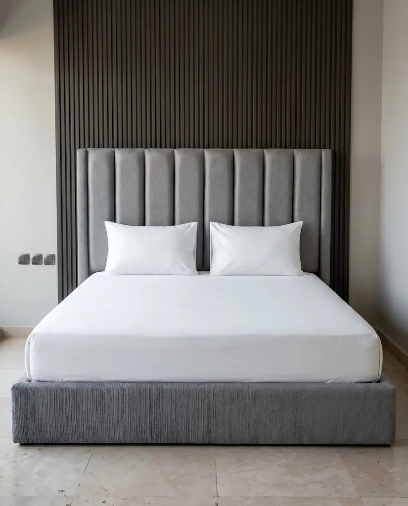 Grey velvet channel-tufted headboard against a dark fluted wall