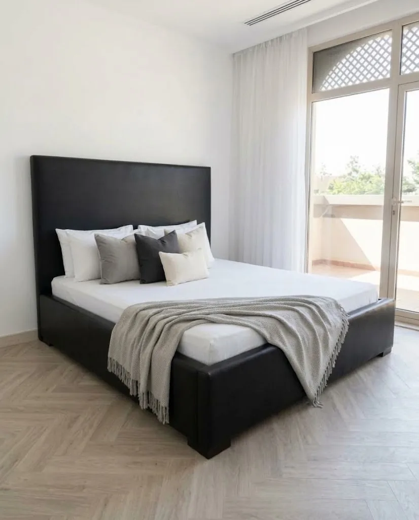 Black upholstered bed with a tall headboard in a bright villa bedroom