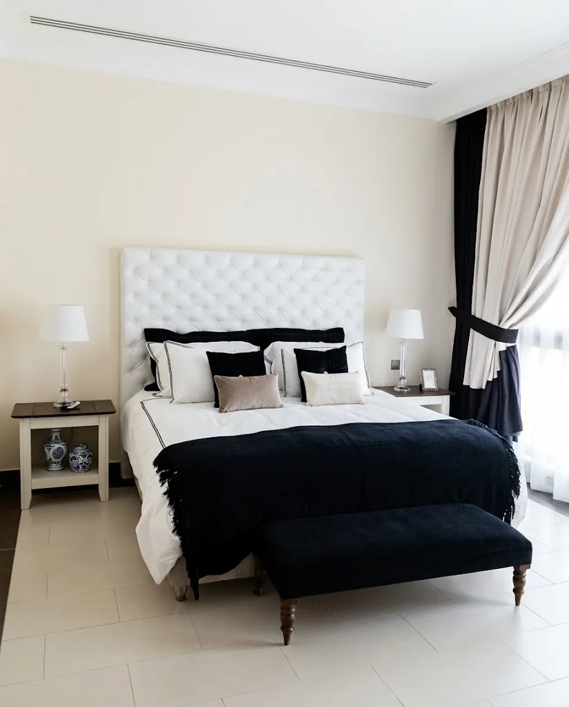 White button-tufted headboard with a navy bench at the foot of the bed