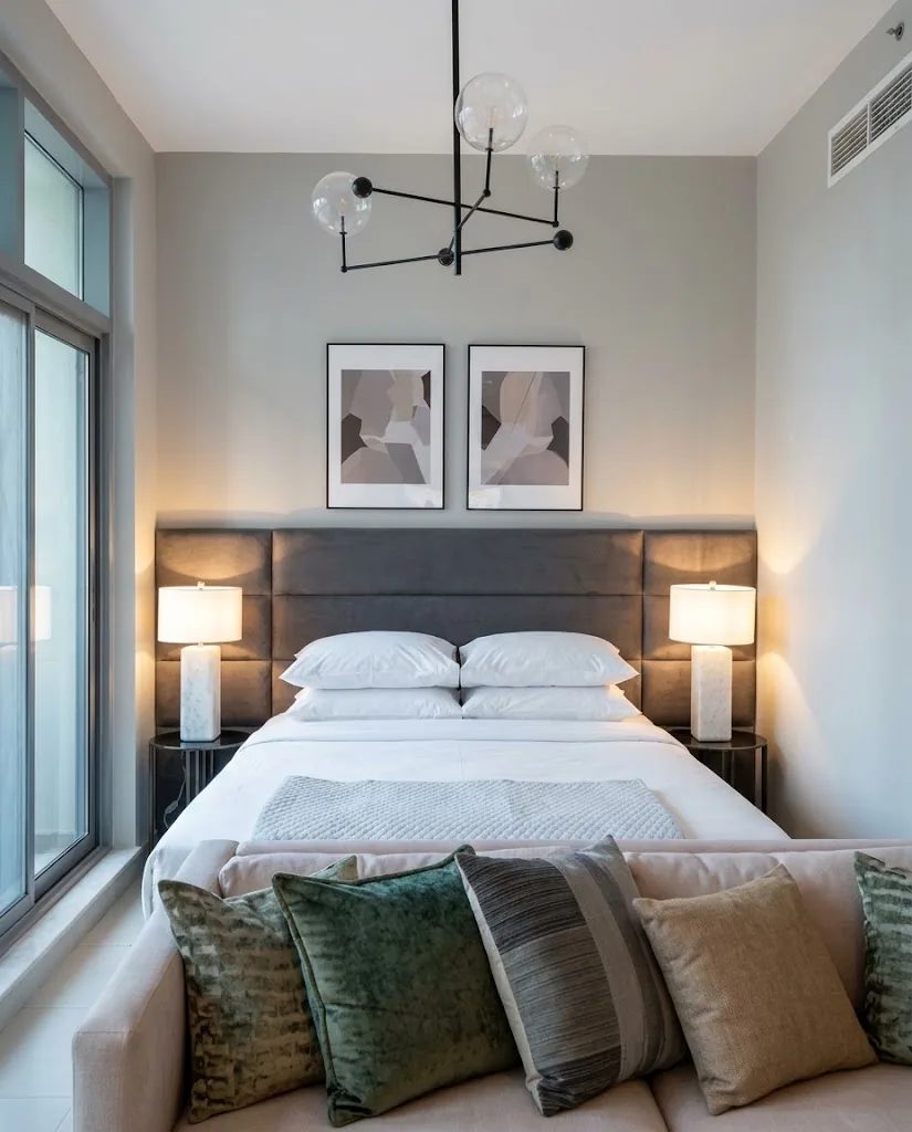 Grey panelled upholstered headboard between bedside lamps