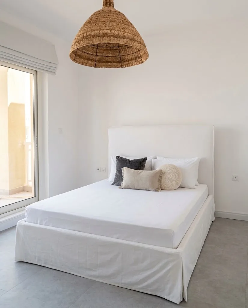 White linen slipcovered bed with a tailored skirt
