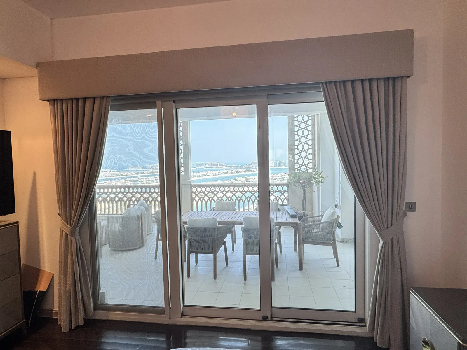 Motorised taupe curtains under a fabric pelmet with a Palm Jumeirah view