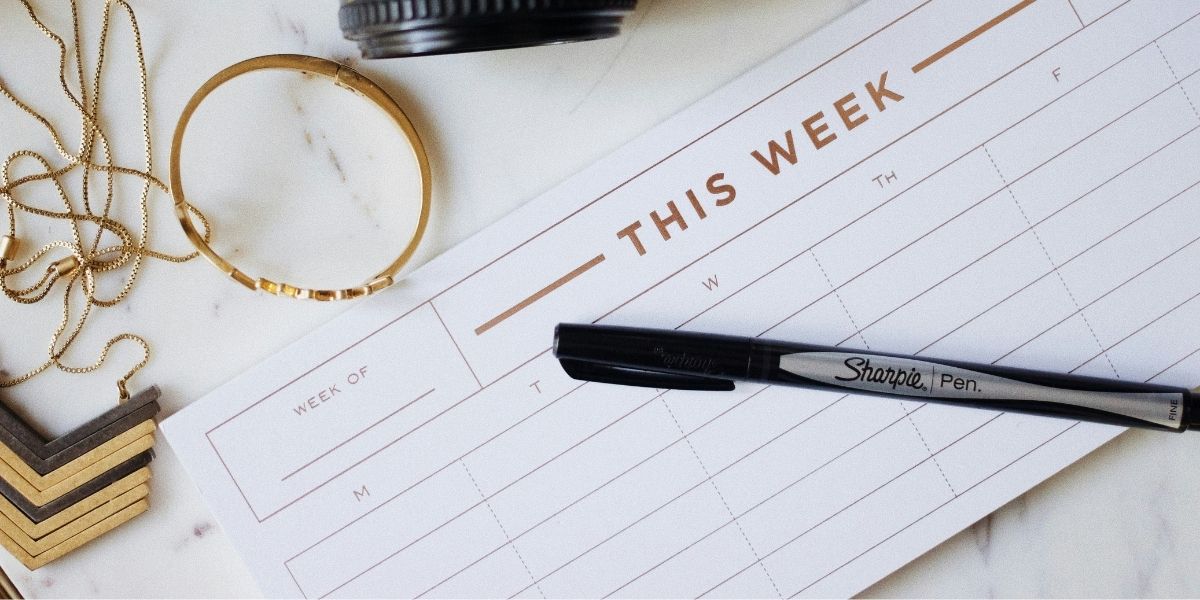 This week calendar on desk with a black sharpie pen and jewelry
