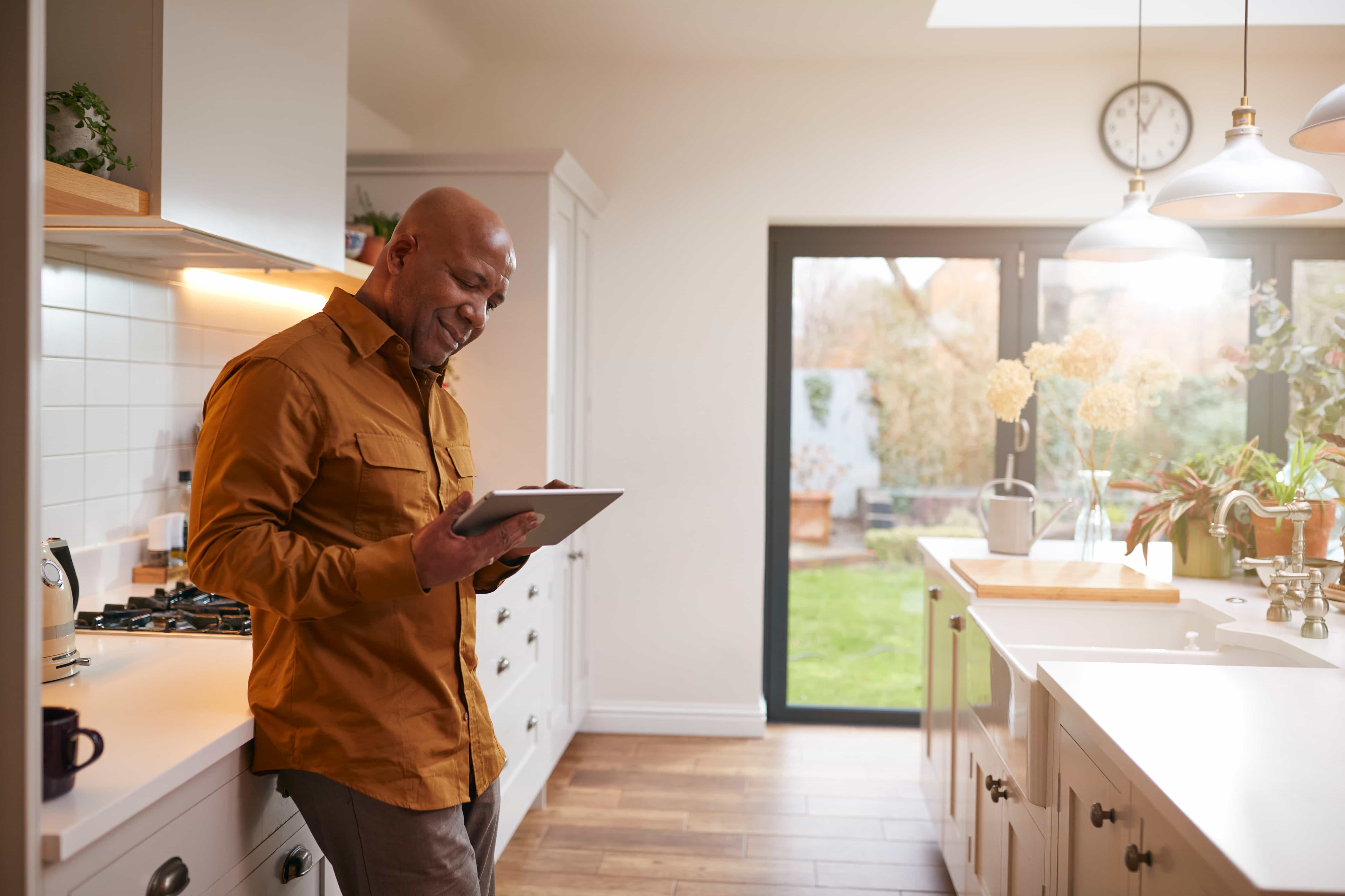 A man standing in a bright, modern residential kitchen in Phoenix, AZ, smiling while using a digital tablet for home service sales strategies. A man standing in a bright, modern residential kitchen in Phoenix, AZ, smiling while using a digital tablet for home service sales strategies.