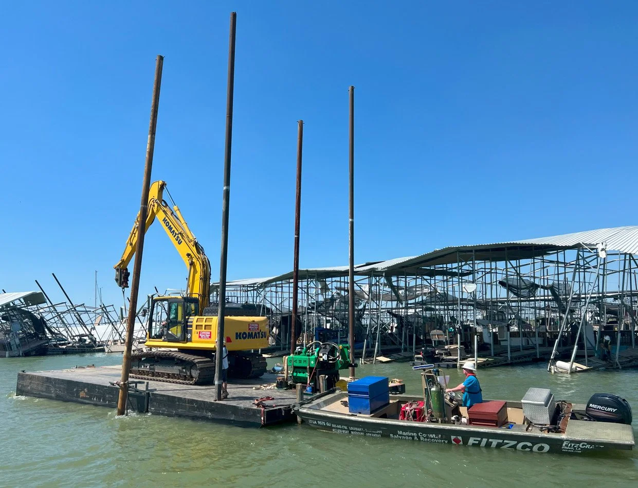 Heavy machinery on a barge fixing a dock that has a lot of storm damage