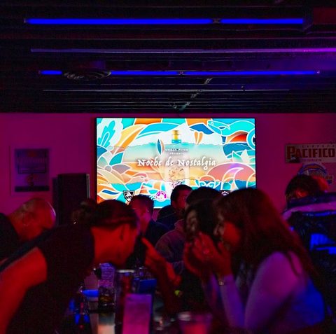 A group celebrating at a table with a colorful mural behind them