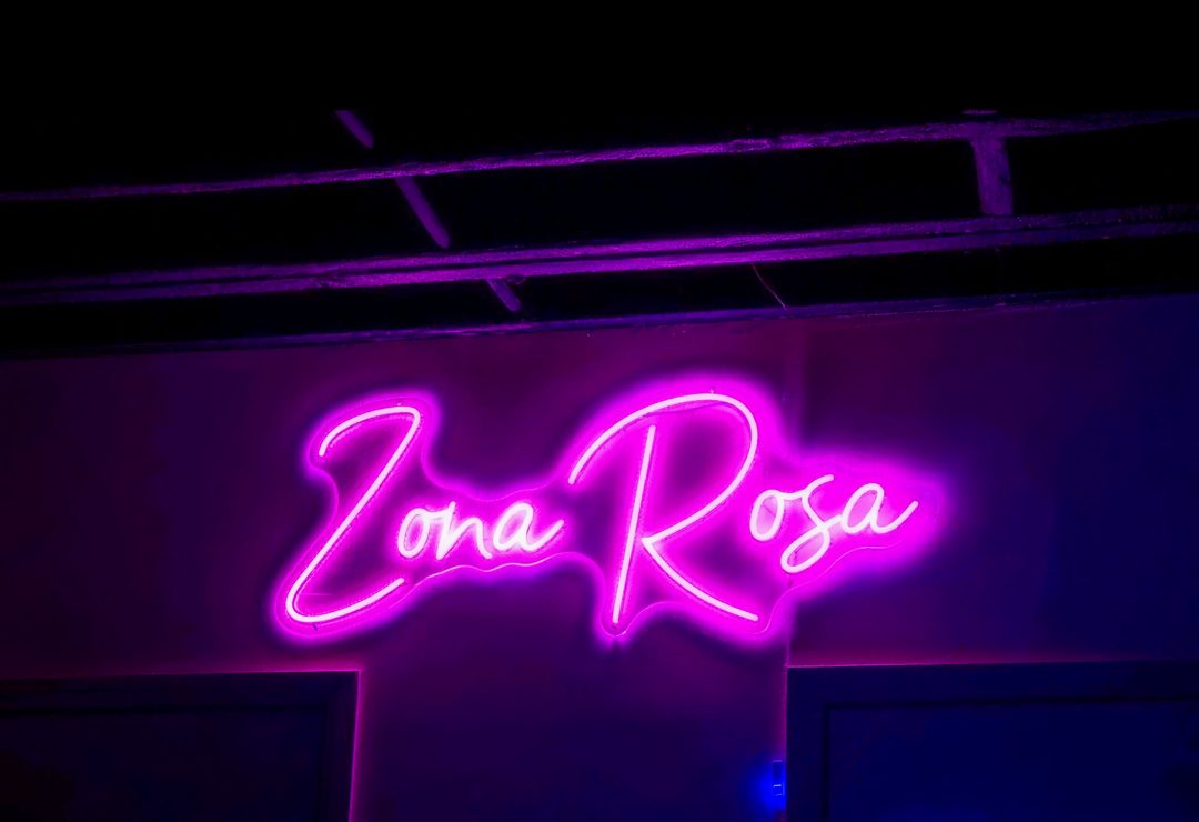 The pink 'Zona Rosa' neon script sign glowing on a wall inside the club