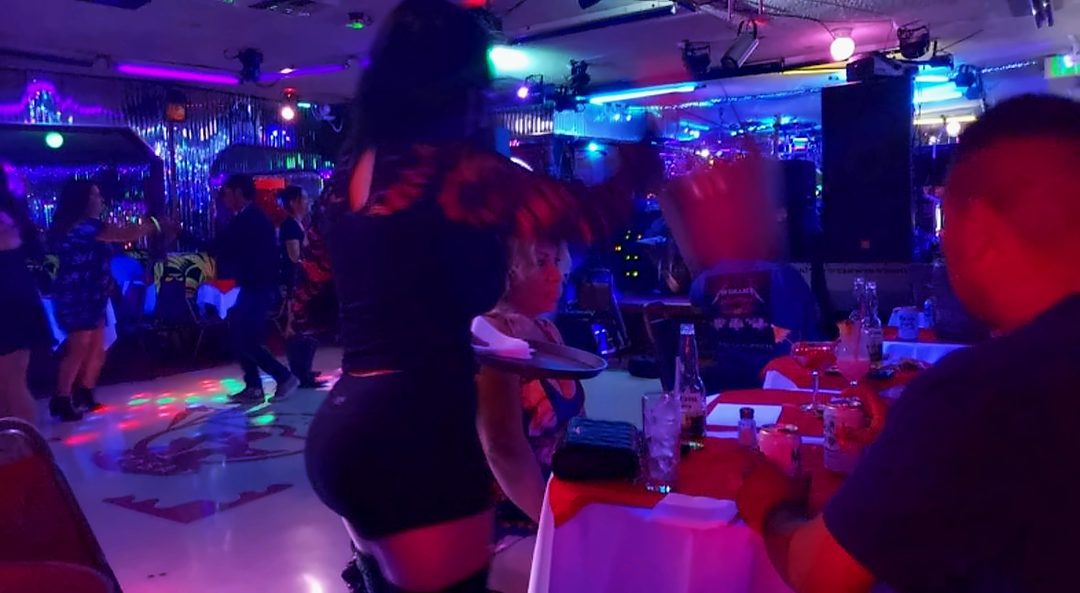 Guests dancing beside the stage at La Zona Rosa with tables and colored lights around the floor