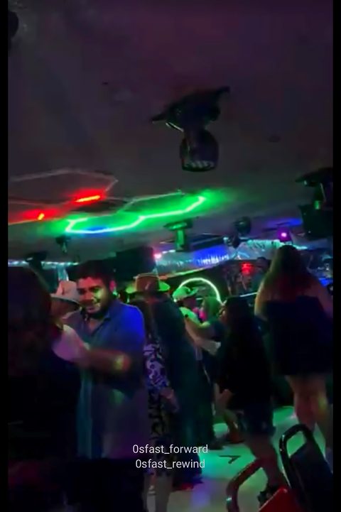 Dancers under green and blue lights on a crowded night