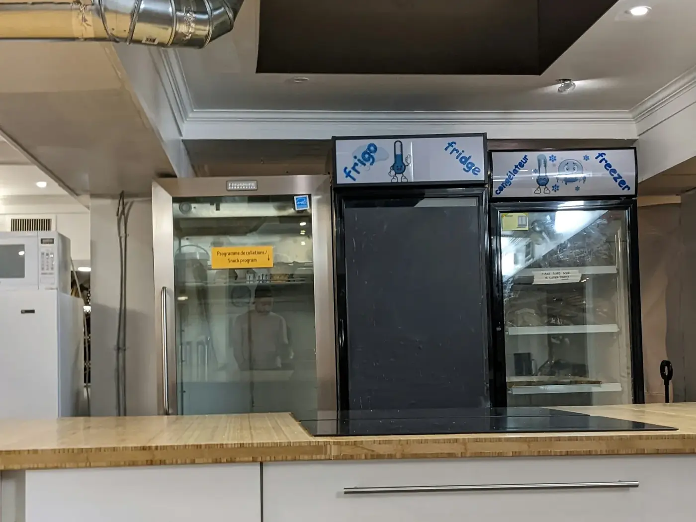 Commercial kitchen with reach-in refrigerators and stainless steel hood