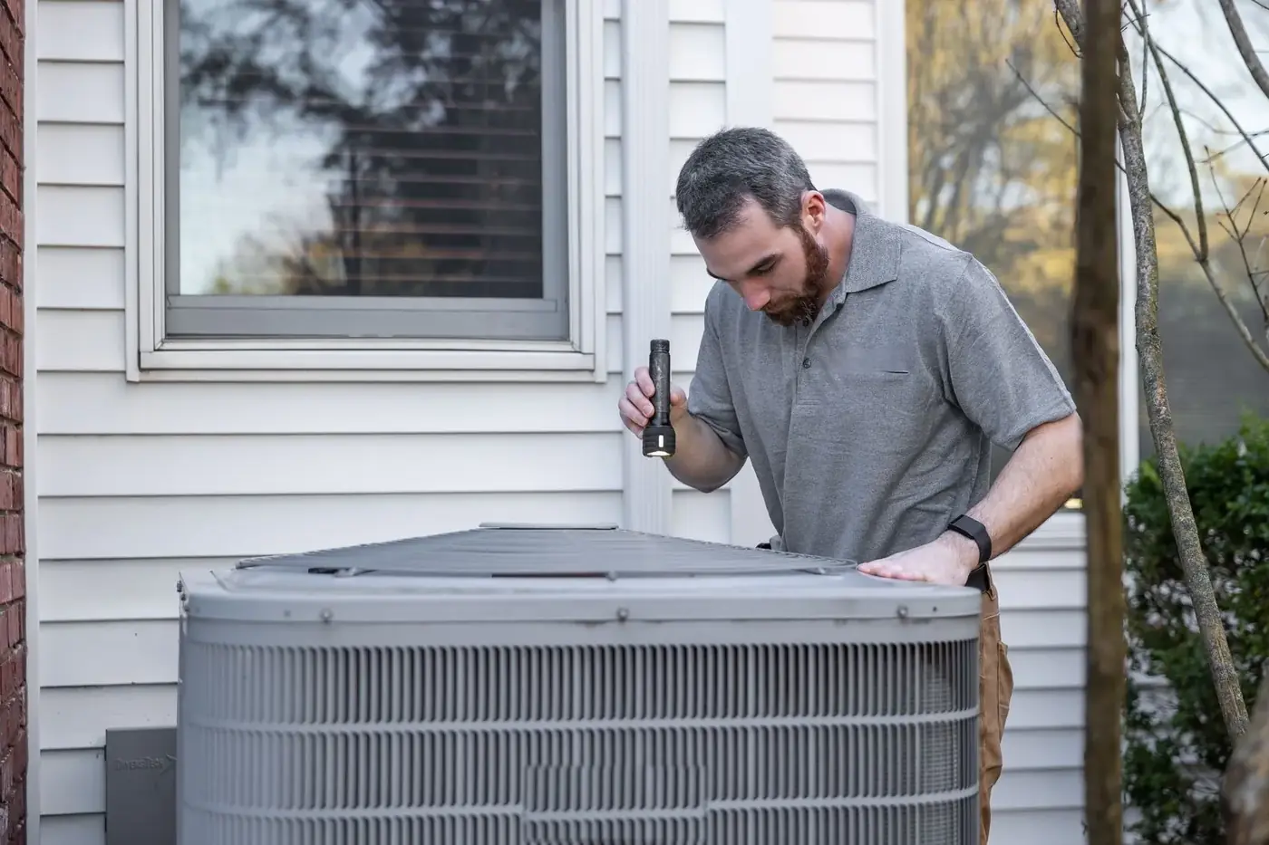 HVAC technician inspecting a residential outdoor AC condenser