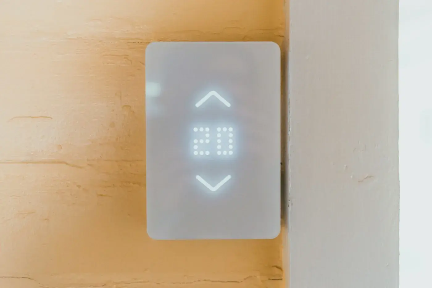 White digital thermostat mounted on a wall