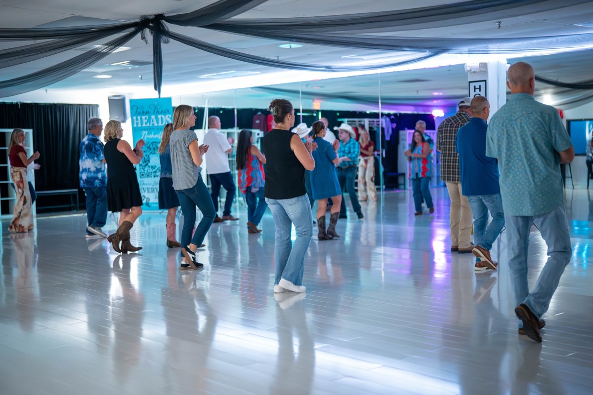 A private group taking a line dance lesson inside the Turn Their Heads Nashville studio.