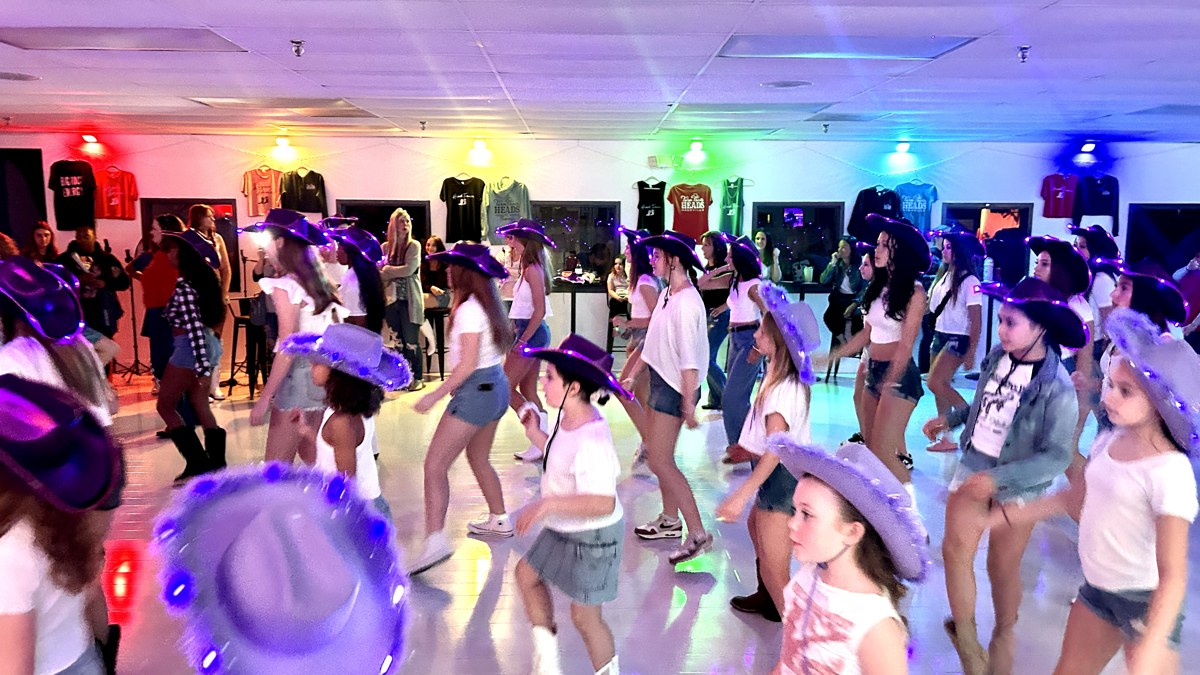 Young participants line dancing in light-up cowboy hats.