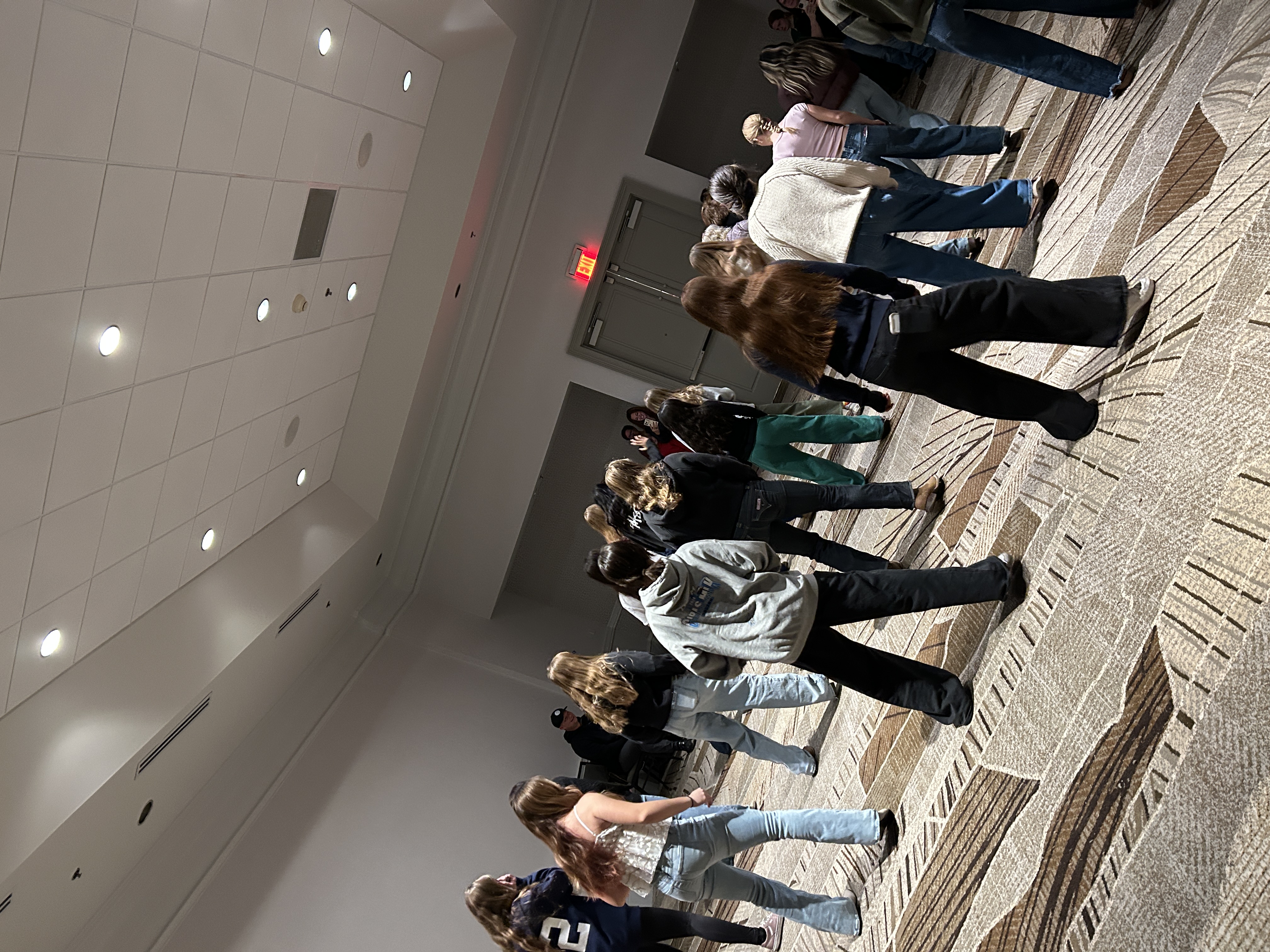 Young team members learning a line dance in a hotel ballroom.