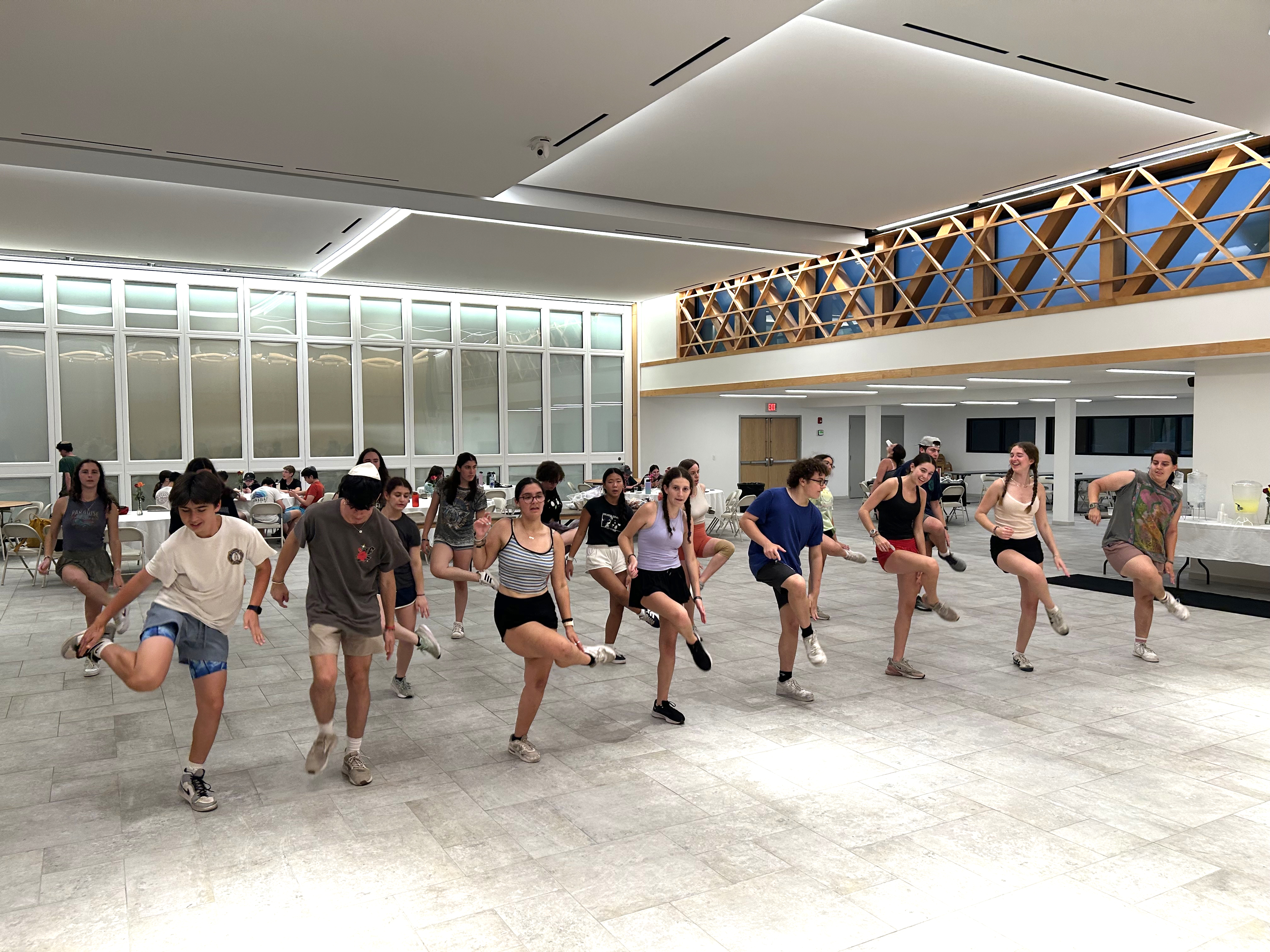A group learning a line dance together in a bright off-site event hall.