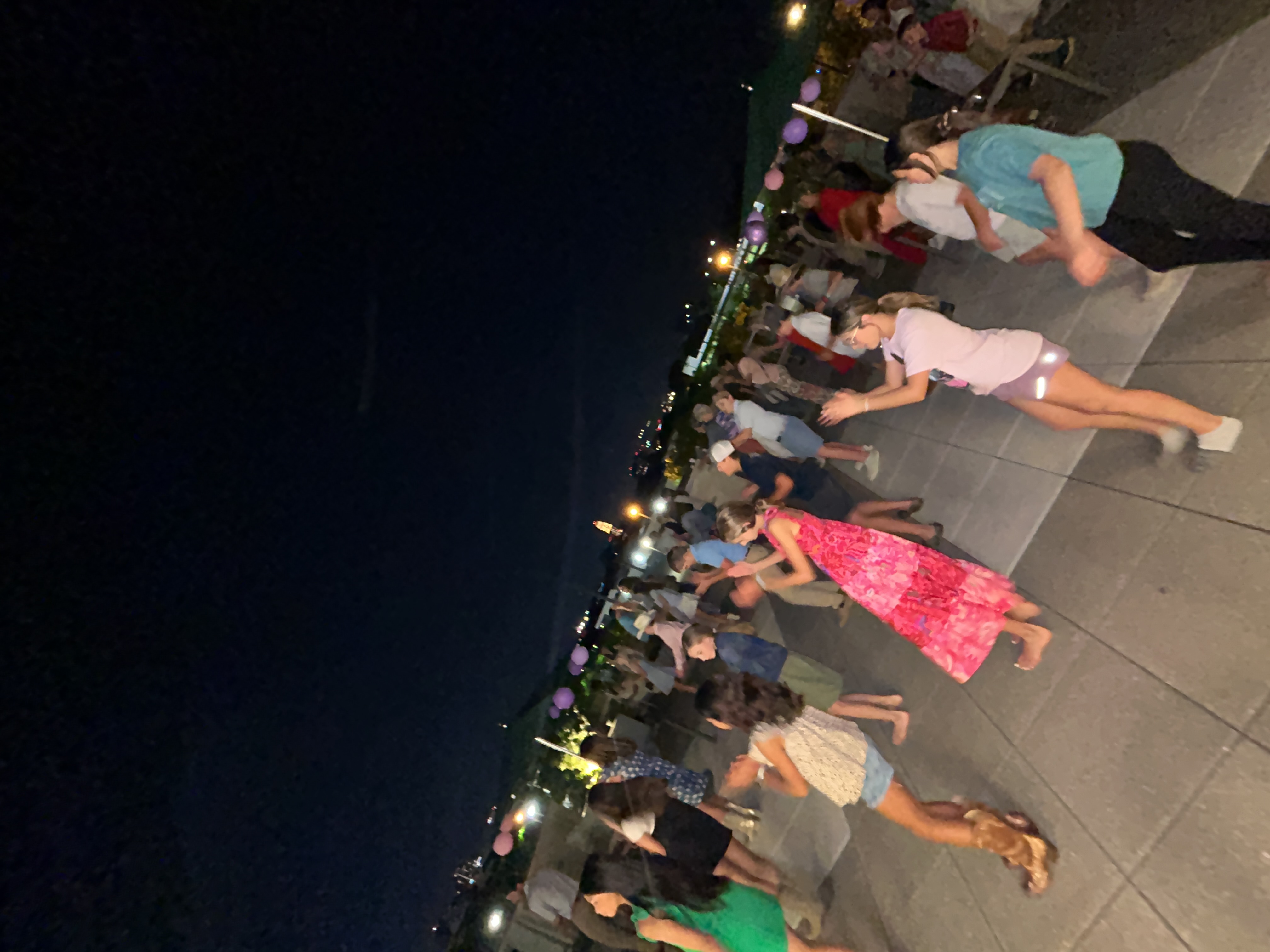 Young dancers following a line dance lesson together on an outdoor rooftop.