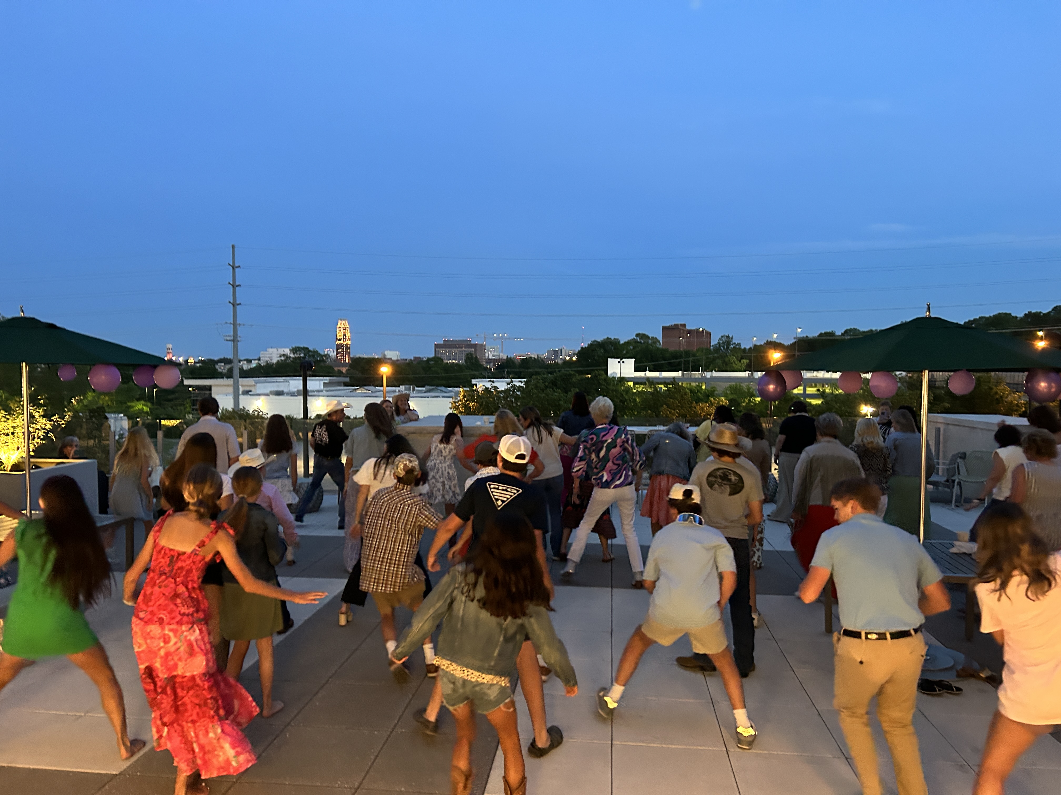 Children practicing line dance steps together during an outdoor rooftop lesson.