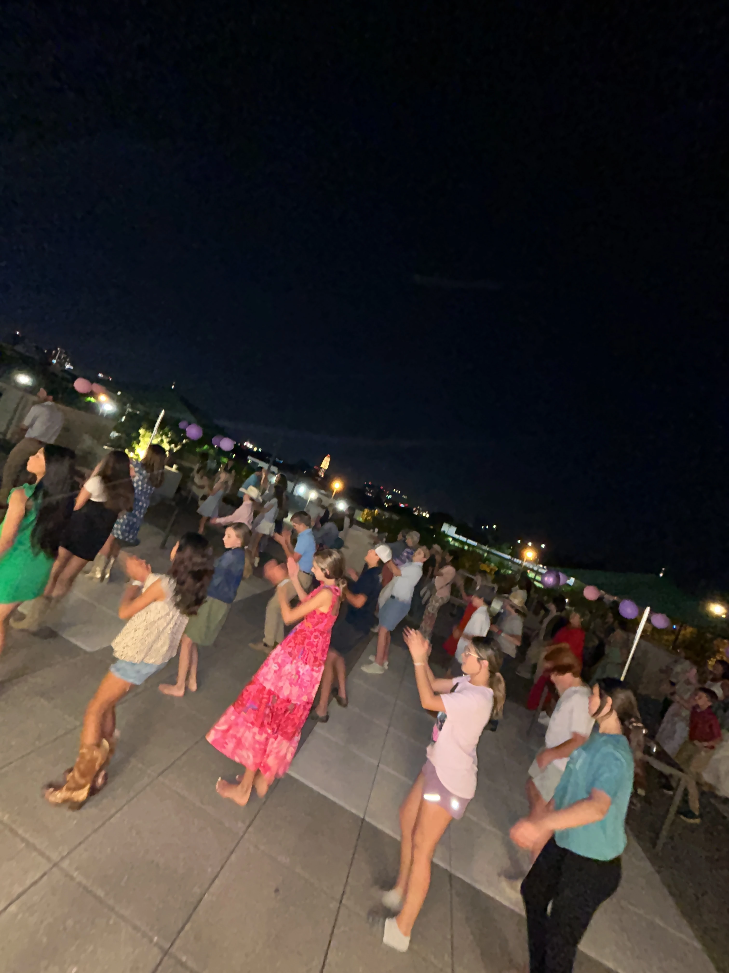 Young dancers following a line dance lesson together on an outdoor rooftop.