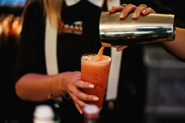 Barkeeperin gießt einen frisch geschüttelten Cocktail ein