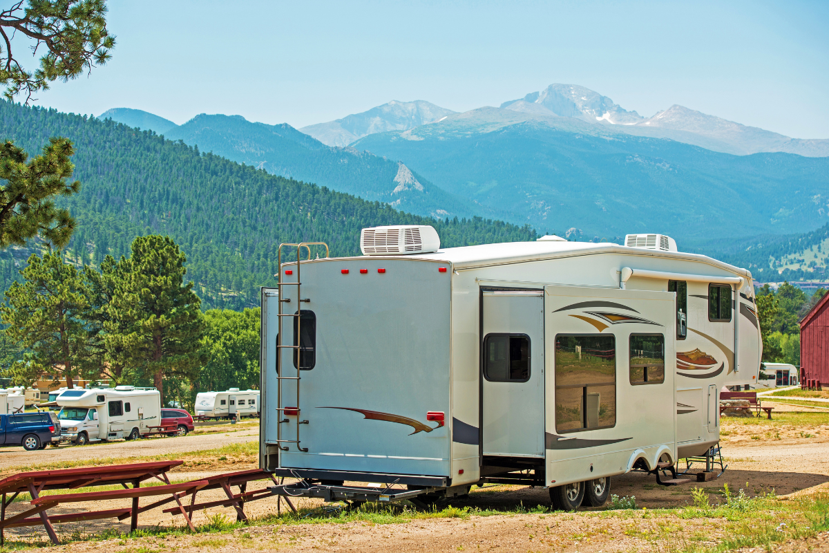 RV at a camp site with mountains in the back ground. RV at a camp site with mountains in the back ground.
