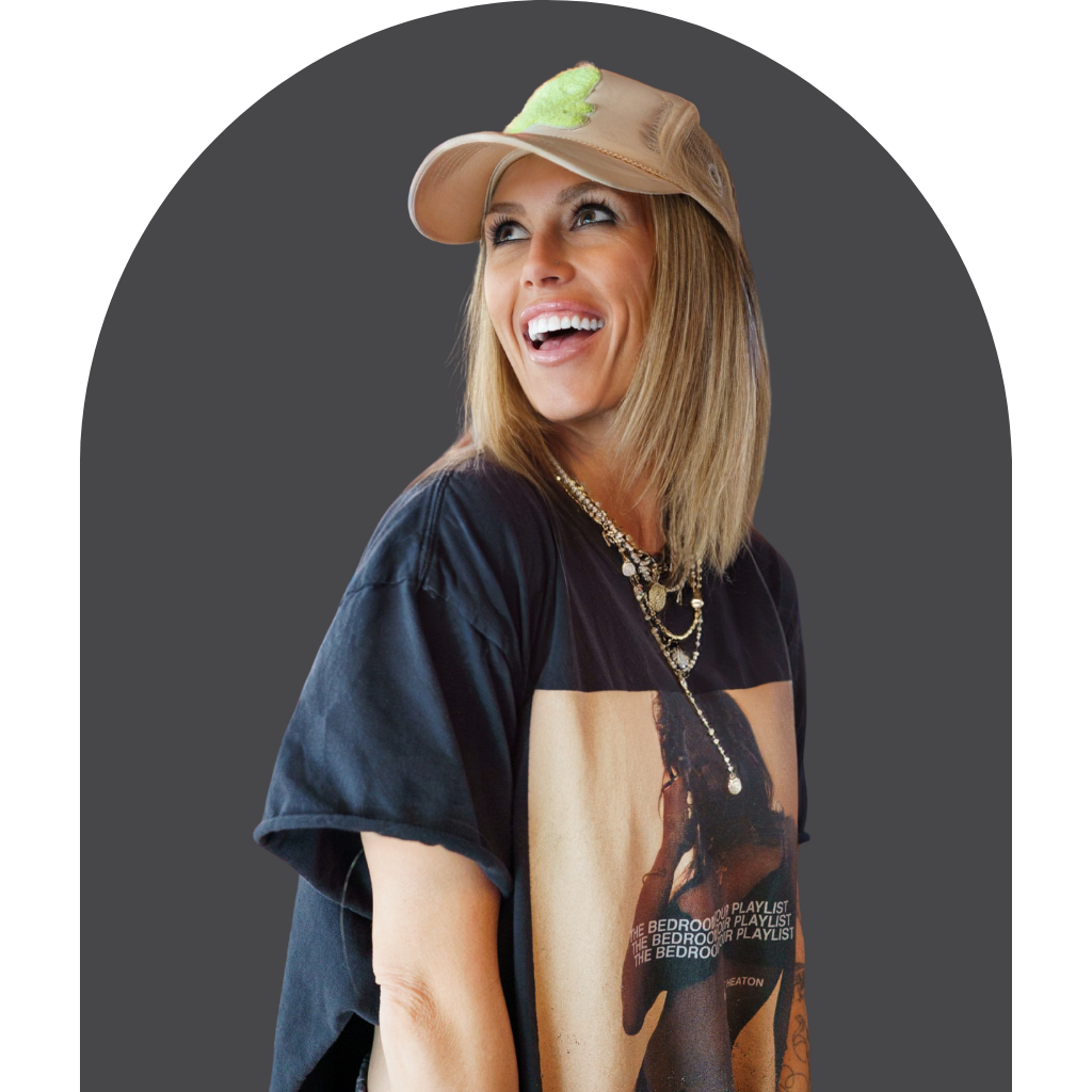 Co-host Gretchen Seeck wearing a black graphic t-shirt and tan baseball cap, smiling in a grey arched frame.