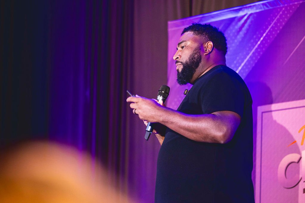 Henry Washington on stage, speaking into a microphone