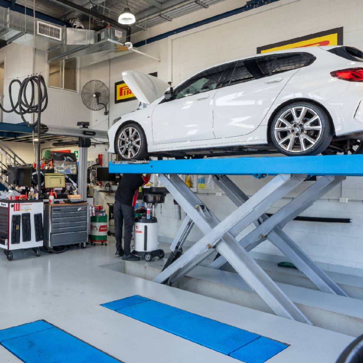 Inside 313 Automotive Russell Lea workshop with cars on hydraulic hoists and technicians working