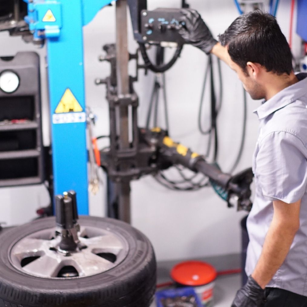 313 Automotive technician inspecting new tyres in workshop, preparing tyres for vehicle fitment in Russell Lea