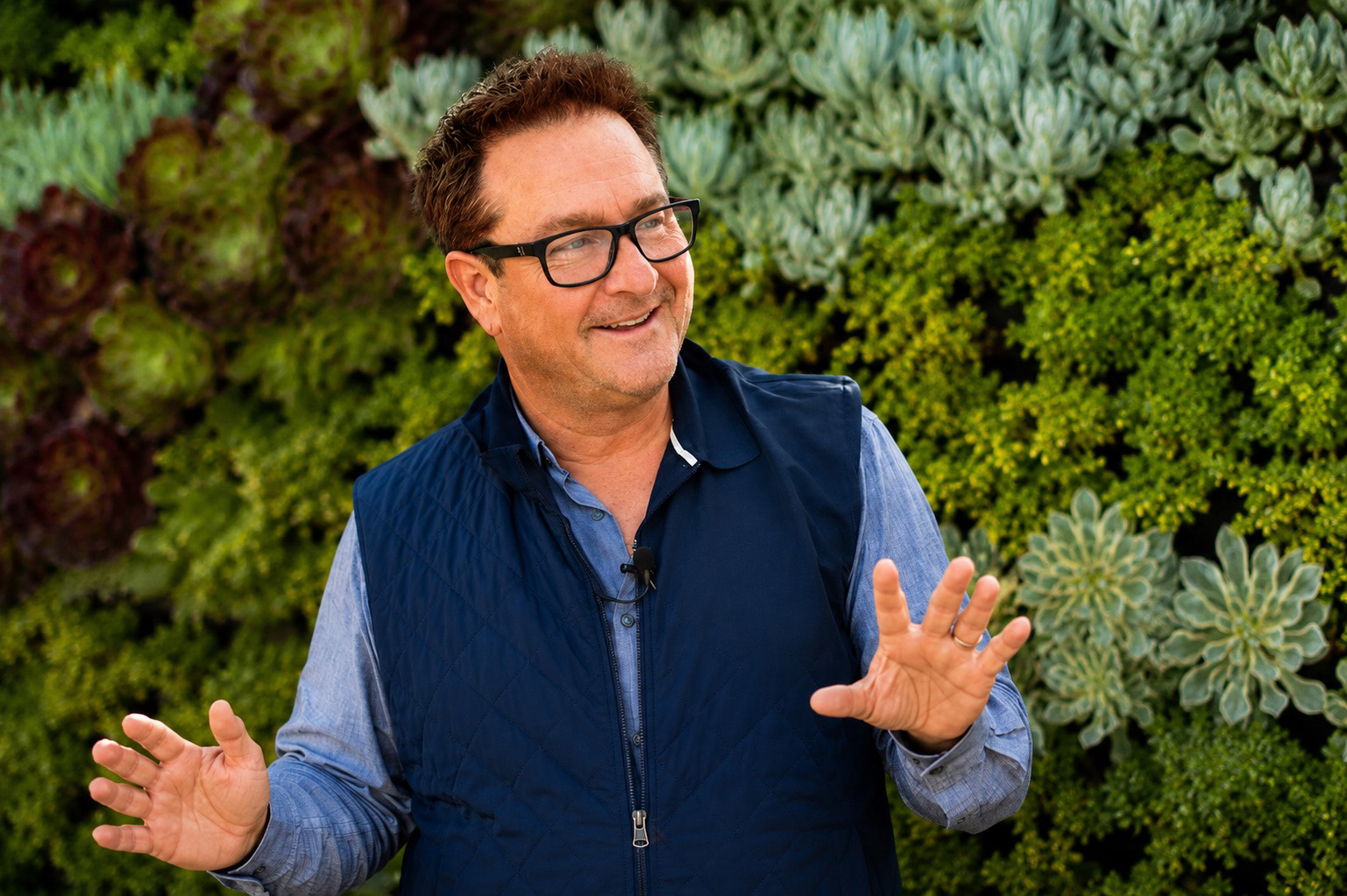 David Bishop speaking in front of a living wall