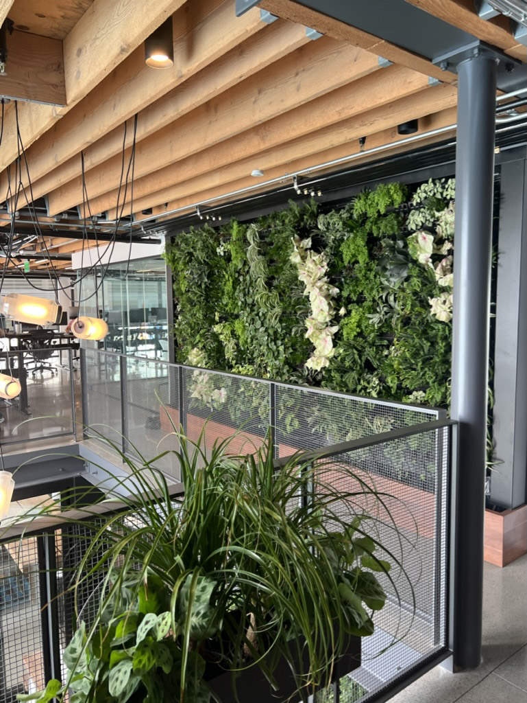 Restaurant living wall with white orchids beside indoor dining and glass railing